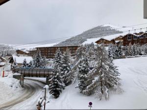 a snow covered town with a bridge and trees at Appartement Alpe Huez 8 personnes centre station in LʼHuez