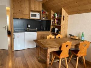 cocina con mesa de madera y 2 sillas en Appartement Alpe Huez 8 personnes centre station en LʼHuez