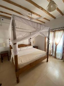 a bedroom with a bed with a canopy at Tembo House - Rafiki Village in Watamu