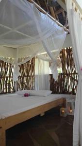 a bedroom with a canopy bed with white curtains at Tembo House - Rafiki Village in Watamu