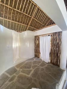 una camera con tetto di paglia e finestra di Tembo House - Rafiki Village a Watamu