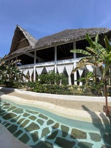 a building with a swimming pool in front of a building at Tembo House - Rafiki Village in Watamu