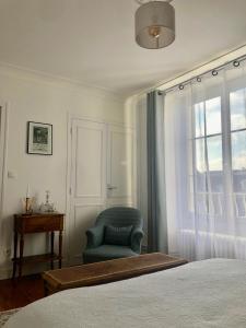 a bedroom with a blue chair and a window at Maison du 7 in Saint-Ouen-en-Belin