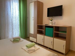 Pokój z telewizorem, łóżkiem i szafką w obiekcie Apartments Luna w mieście Pag