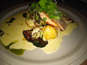 a plate of food with fish with sauce and broccoli at Ellivuori, Ellin Pooli 5 in Sastamala