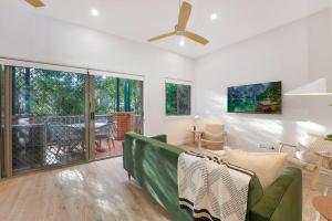 a living room with a green couch and a large window at On the Brook - Private 2 bed + loft and pool in Brisbane