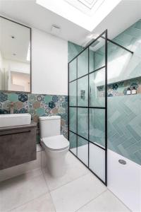 a bathroom with a toilet and a glass shower at Cozy Leyton House with Garden and Small Terrace in London
