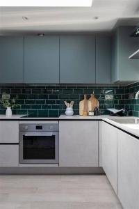 a kitchen with white cabinets and green tiles at Cozy Leyton House with Garden and Small Terrace in London