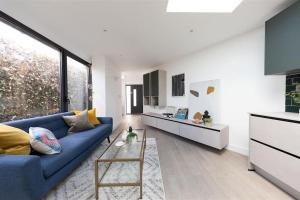 a living room with a blue couch and a kitchen at Cozy Leyton House with Garden and Small Terrace in London