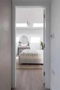 a white bedroom with a bed and a mirror at Cozy Leyton House with Garden and Small Terrace in London