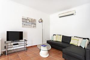 ein Wohnzimmer mit einem schwarzen Sofa und einem Flachbild-TV in der Unterkunft Gardénia Apartment in Santa Luzia