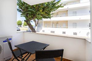 einen Tisch und Stühle auf einem Balkon mit einem Baum in der Unterkunft Gardénia Apartment in Santa Luzia