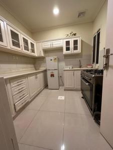 a kitchen with white cabinets and a stove and refrigerator at شقه بغرفة نوم تسجيل دخول ذاتي in Ar Rākah