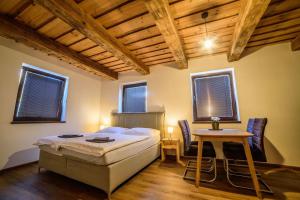 - une chambre avec un lit, une table et des fenêtres dans l'établissement Apartmány Faustin, à Kvilda