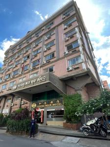 a building with a woman standing in front of it at Chung Hsin Hotel 中信酒店 in Phnom Penh