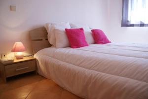 1 dormitorio con 1 cama con almohadas rosas y lámpara en Quinta da Gomeira, en Cabanas de Tavira