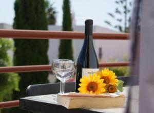 una botella de vino y una copa y girasoles sobre una mesa en Quinta da Gomeira, en Cabanas de Tavira