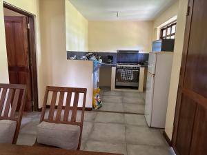a kitchen with a refrigerator and a table and chairs at Garden Beach Apartment Zanzibar in Pwani Mchangani