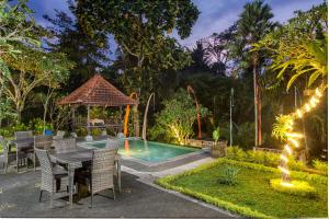un patio trasero con mesa, sillas y piscina en Alas Petulu Villa Resort and Spa, en Ubud