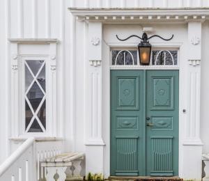 a green door on a white house with a lamp at Kinna Bed & Breakfast in Kinna