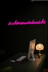 un'insegna al neon su una scrivania con un computer e una lampada di DAS SCHÖNE LEBEN Pop-Up Hotel a Hornberg