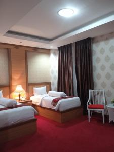 a hotel room with two beds and a chair at Grand Buana Lestari Hotel in Duku