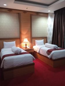 a hotel room with two beds and a lamp at Grand Buana Lestari Hotel in Duku