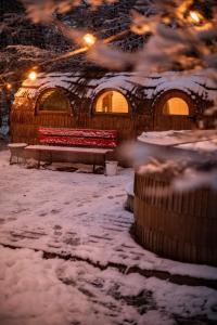a snow covered building with a bench and lights at DAS SCHÖNE LEBEN Pop-Up Hotel in Hornberg