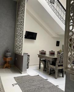 een woonkamer met een tafel en een tv aan de muur bij Riad Darnooz in Marrakesh