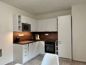 a kitchen with white cabinets and a white chair at Apartmány Victory Residence in Prosečné