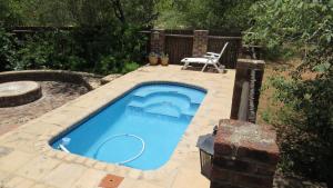 a swimming pool with a table and a chair in a yard at Crowe's Nest in Marloth Park