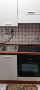 a kitchen with a sink and a stove at Ampio monolocale con terrazzo - a 2 passi dal mare in Latte +15 photos