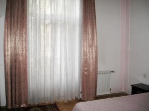a bedroom with a white curtain and a bed at Apartment on Tumanyan in Yerevan