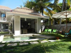 a backyard with a swimming pool and an umbrella at Modern Villa with service. Exceptional beach, private swimming pool in Roches Noires
