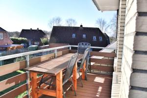 eine Terrasse mit einem Holztisch und Stühlen auf dem Balkon in der Unterkunft Nordsee Anker Unsere moderne 87 qm Ferienwohnung mit zwei Schlafzimmer in Norden Ortsteil Ostermarsch in Norden
