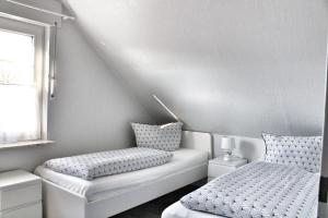 Dieses weiße Zimmer verfügt über 2 Betten und ein Fenster. in der Unterkunft Nordsee Anker Unsere moderne 87 qm Ferienwohnung mit zwei Schlafzimmer in Norden Ortsteil Ostermarsch in Norden