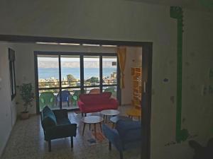 een woonkamer met stoelen en tafels en een raam bij turtle guesthouse- tiberias in Tiberias