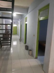 un corridoio vuoto con porte verdi e pareti bianche di Hotel Griya Syar'i a Pekalongan