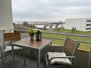 a table and chairs on a balcony with a view at Quartier Südstrand - Ferienwohnung mit Meerblick in Fehmarn