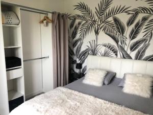 a bedroom with a bed with a mural of palm trees at Cottage l'Echappée Belle in Saint-Amand-les-Eaux