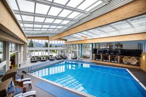 an indoor swimming pool with a glass ceiling at Schlosshotel Lacknerhof in Flachau