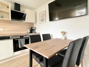 a kitchen with a wooden table and black chairs at Geruhsam, Sonnig & Zentral - 3-Zimmer-Apartment in Graal-Müritz