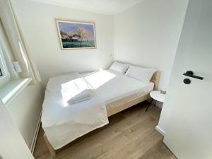 a small bedroom with a white bed and a window at Geruhsam, Sonnig & Zentral - 3-Zimmer-Apartment in Graal-Müritz