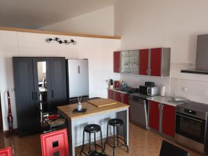 uma cozinha com armários vermelhos e um balcão com bancos em SUNNY GAPI APP em Barbariga
