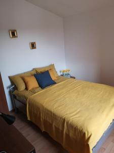 バーバリガにあるSUNNY GAPI APPのベッドルーム1室(大型ベッド1台、黄色いシーツ、青い枕付)