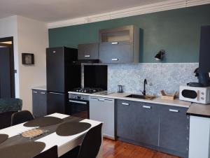 a kitchen with stainless steel appliances and a table at Appartement moderne in Le Puy-en-Velay