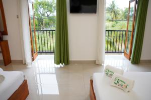 a room with two beds and a tv and a balcony at J leaf Hotel by Blue Bird in Negombo