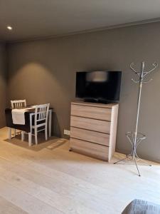 un salon avec une télévision sur une commode avec un bureau dans l'établissement Stilren suite med egen inngang og kokemuligheter., à Tromsø