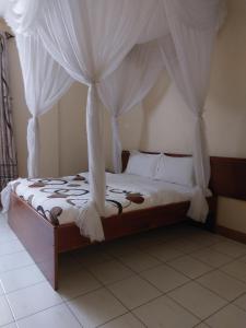 Roza Guest House في نيفاشا: غرفة نوم مع سرير مظلة مع ستائر بيضاء