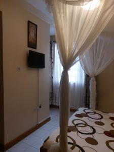 a bedroom with a bed with curtains and a television at Roza Guest House in Naivasha